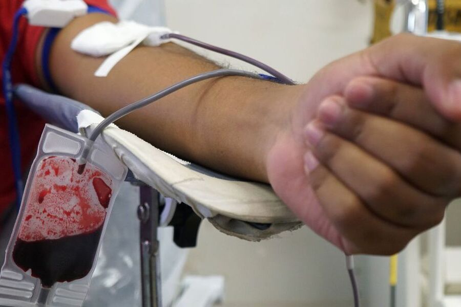 Pessoa, com o braço estendido, doa sangue