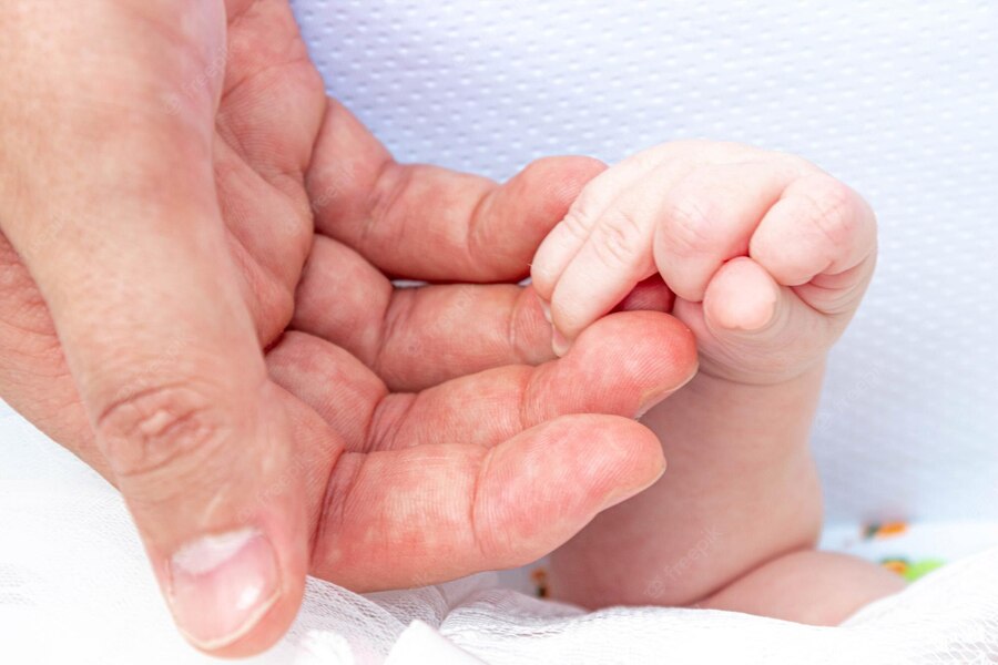 Foto de mão masculina segurando nas mãos de um bebê recém-nascido