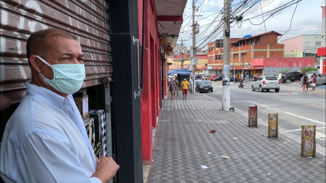 Cidadão de máscara parado em frente a uma loja fechada na Brasilandia